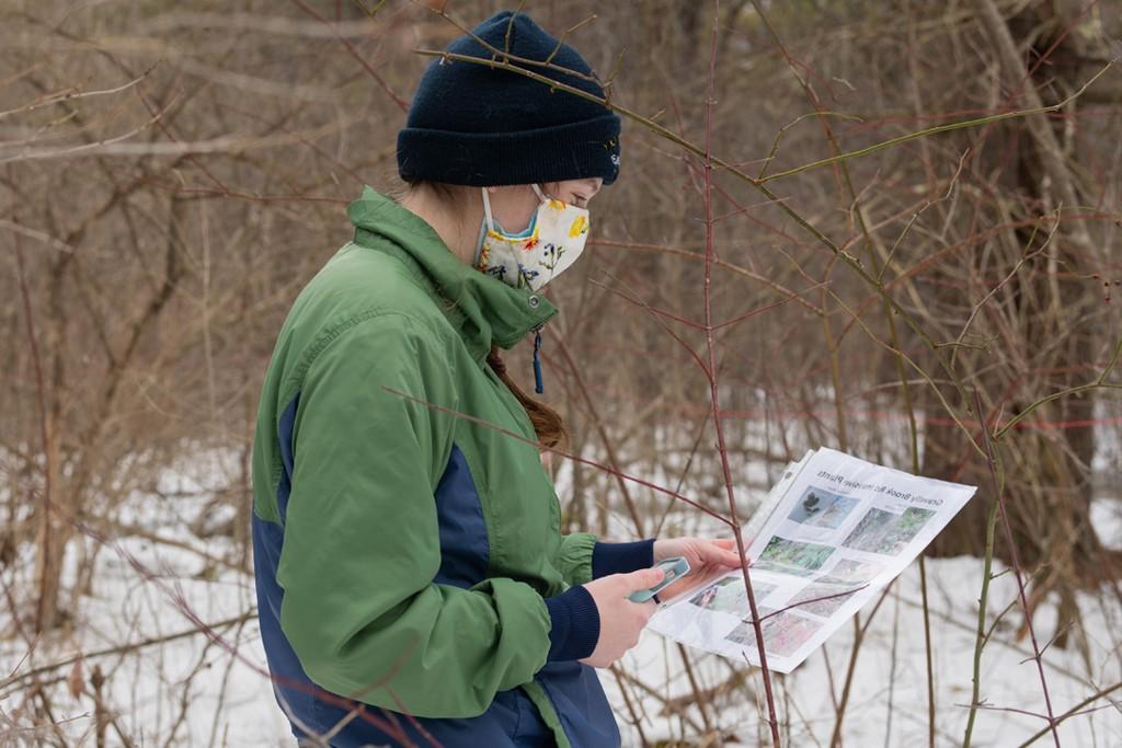 A student standing outside in the snow examines a informational flyer about birds